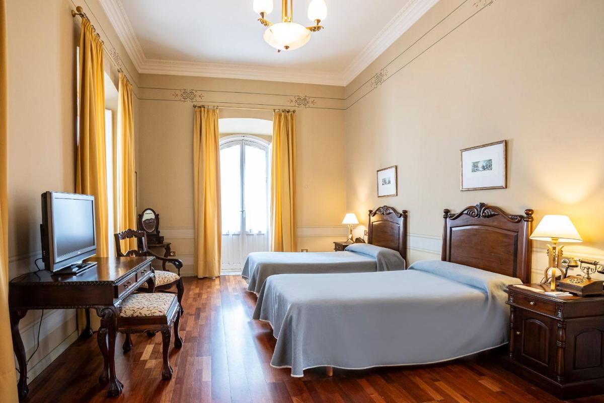 Una habitación de hotel con dos camas y un televisor. en Hotel Mirador de Llerena, en Llerena