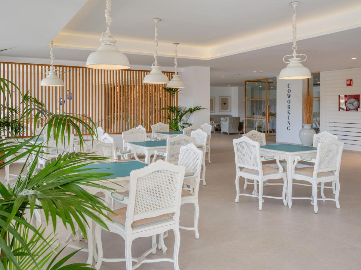 Un comedor con mesas blancas y sillas blancas. en Grupotel Maritimo, en Puerto de Alcudia