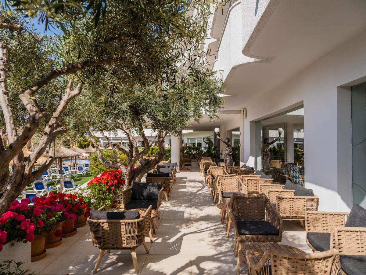 Una hilera de sillas y flores en un patio. en Grupotel Maritimo, en Puerto de Alcudia
