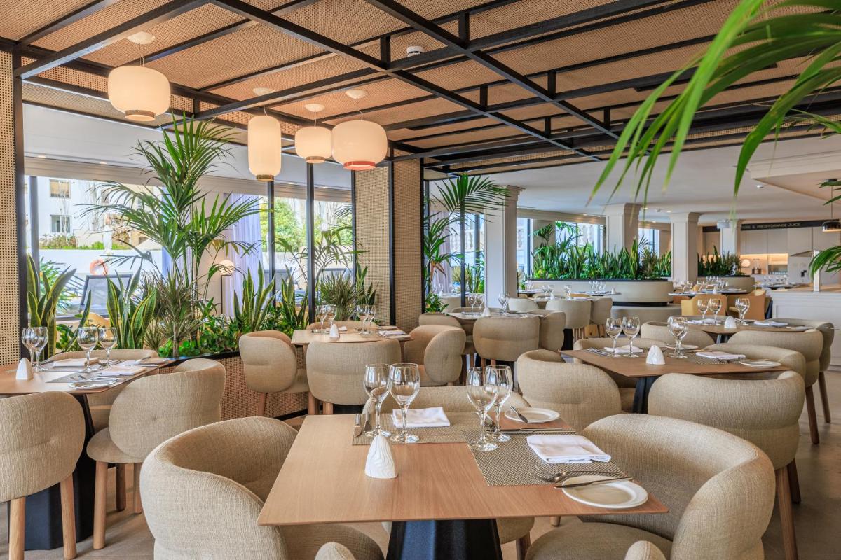 Un restaurante con mesas, sillas y plantas. en Hotel Illa d'Or & Club Apts 4* Sup, en Puerto Pollensa