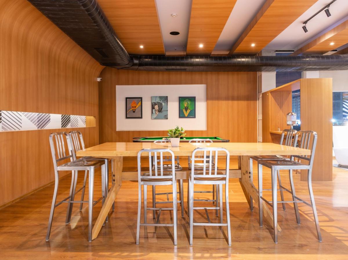 a dining room with a wooden table and stools at Sunday Hotel Chandigarh Zirakpur in Zirakpur