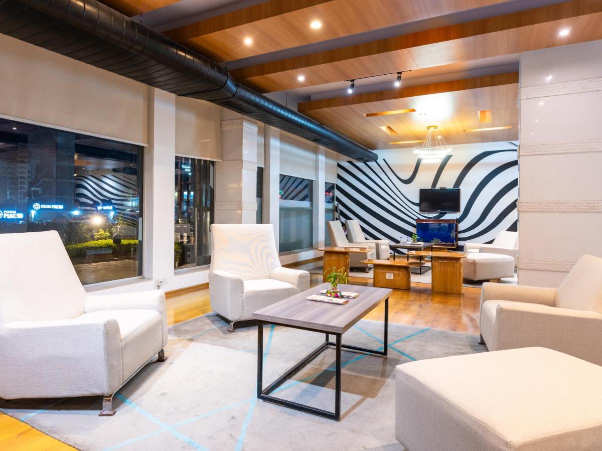 a living room with white furniture and a tv at Sunday Hotel Chandigarh Zirakpur in Zirakpur