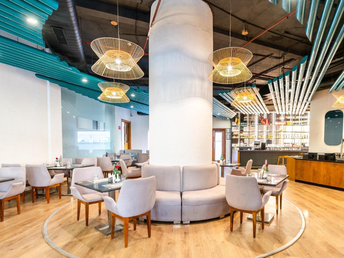 a restaurant with white chairs and tables and a column at Sunday Hotel Chandigarh Zirakpur in Zirakpur