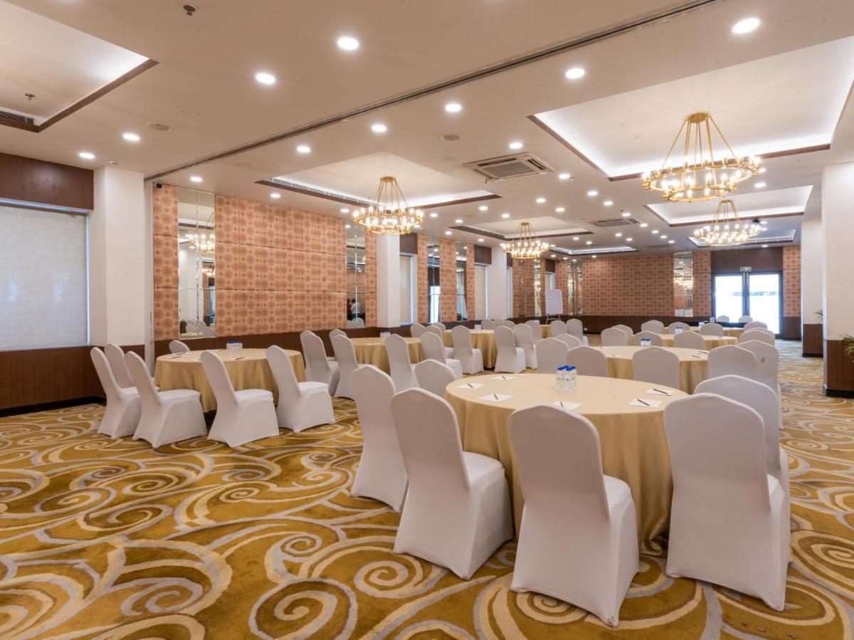 a conference room with tables and chairs and a screen at Sunday Hotel Chandigarh Zirakpur in Zirakpur