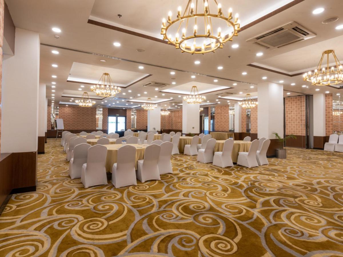 a banquet hall with tables and chairs and chandeliers at Sunday Hotel Chandigarh Zirakpur in Zirakpur