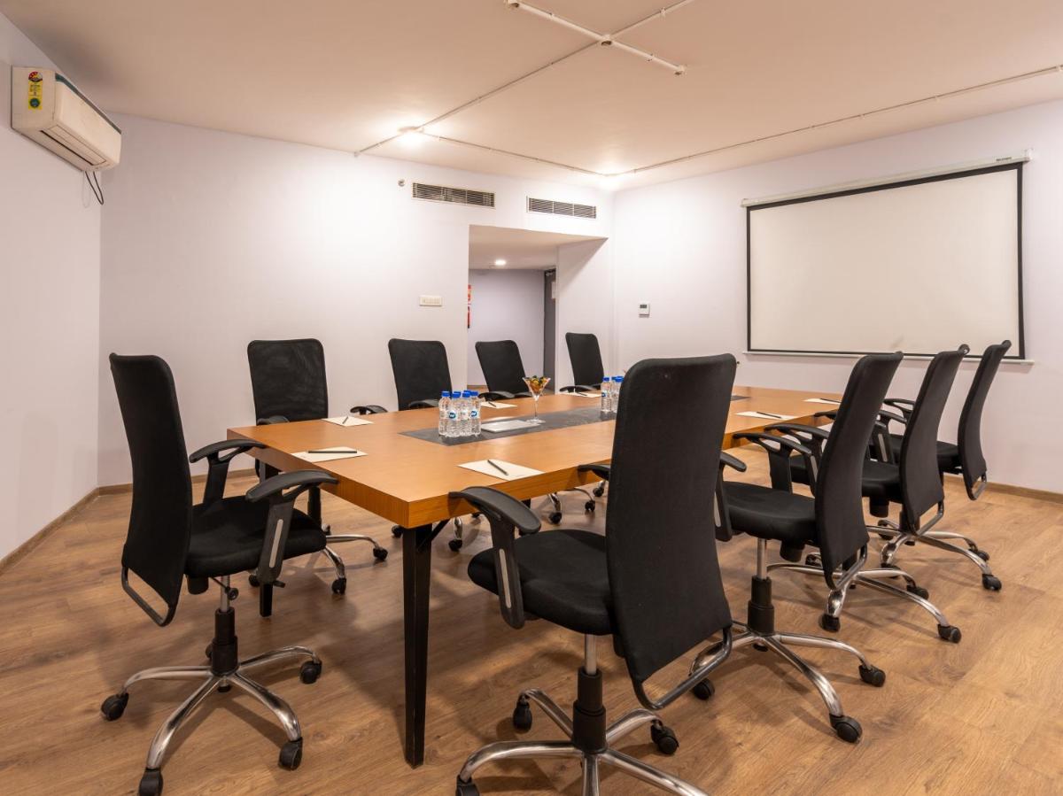 a conference room with a wooden table and black chairs at Sunday Hotel Chandigarh Zirakpur in Zirakpur