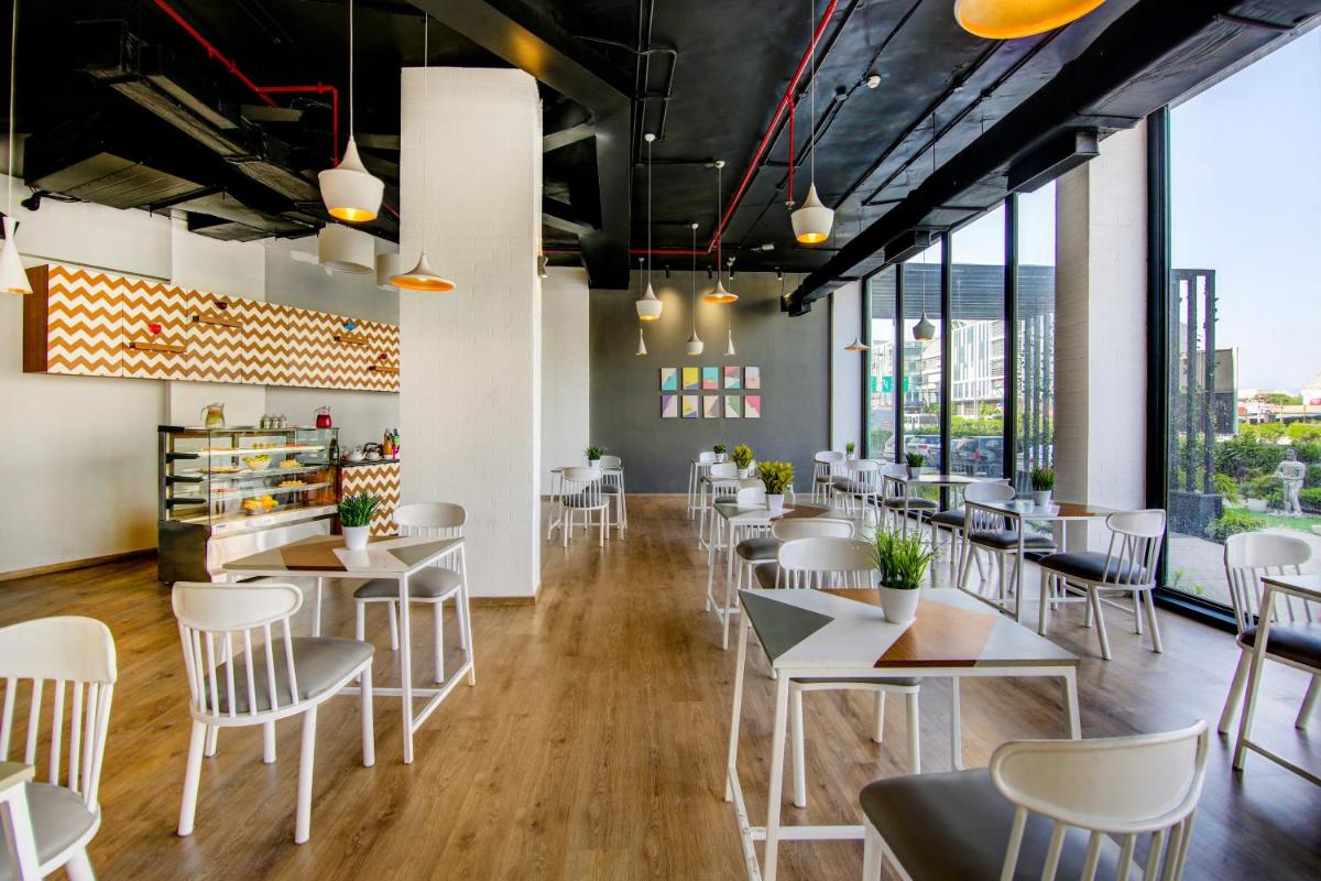 a restaurant with white tables and chairs and large windows at Sunday Hotel Chandigarh Zirakpur in Zirakpur