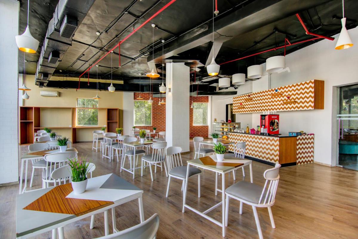 a restaurant with white chairs and tables and a bar at Sunday Hotel Chandigarh Zirakpur in Zirakpur