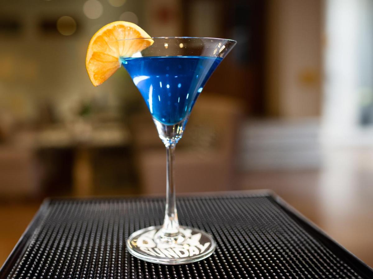 a blue drink in a martini glass with an orange slice at Sunday Hotel Chandigarh Zirakpur in Zirakpur