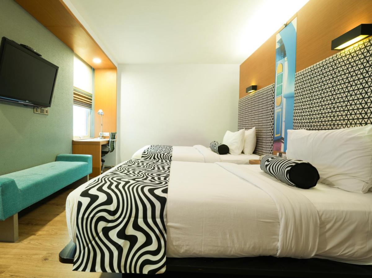 a hotel room with two beds and a flat screen tv at Sunday Hotel Chandigarh Zirakpur in Zirakpur