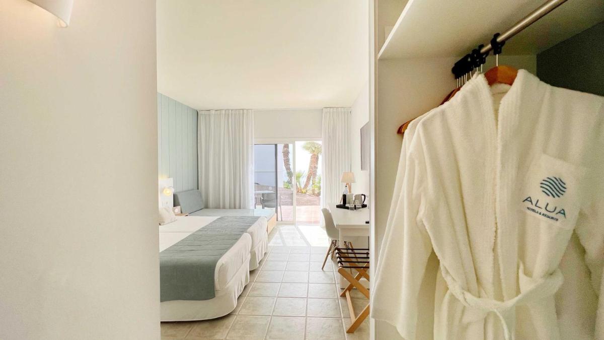 Habitación de hotel con cama y albornoz en Alua Village Fuerteventura - All Inclusive, en Playa de Jandía