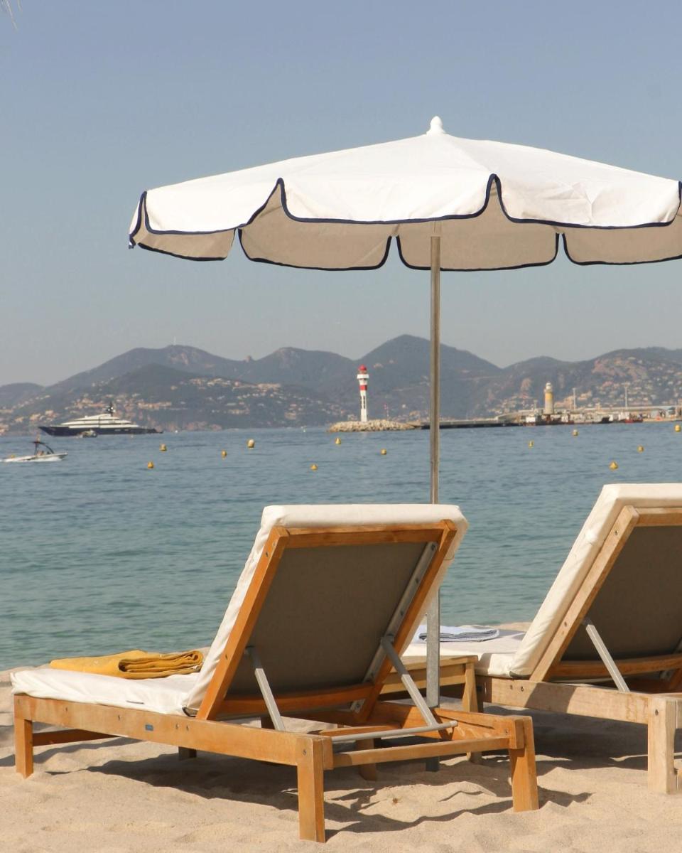 - deux chaises longues et un parasol sur une plage dans l'établissement Five Seas Cannes, a Member of Design Hotels™, à Cannes