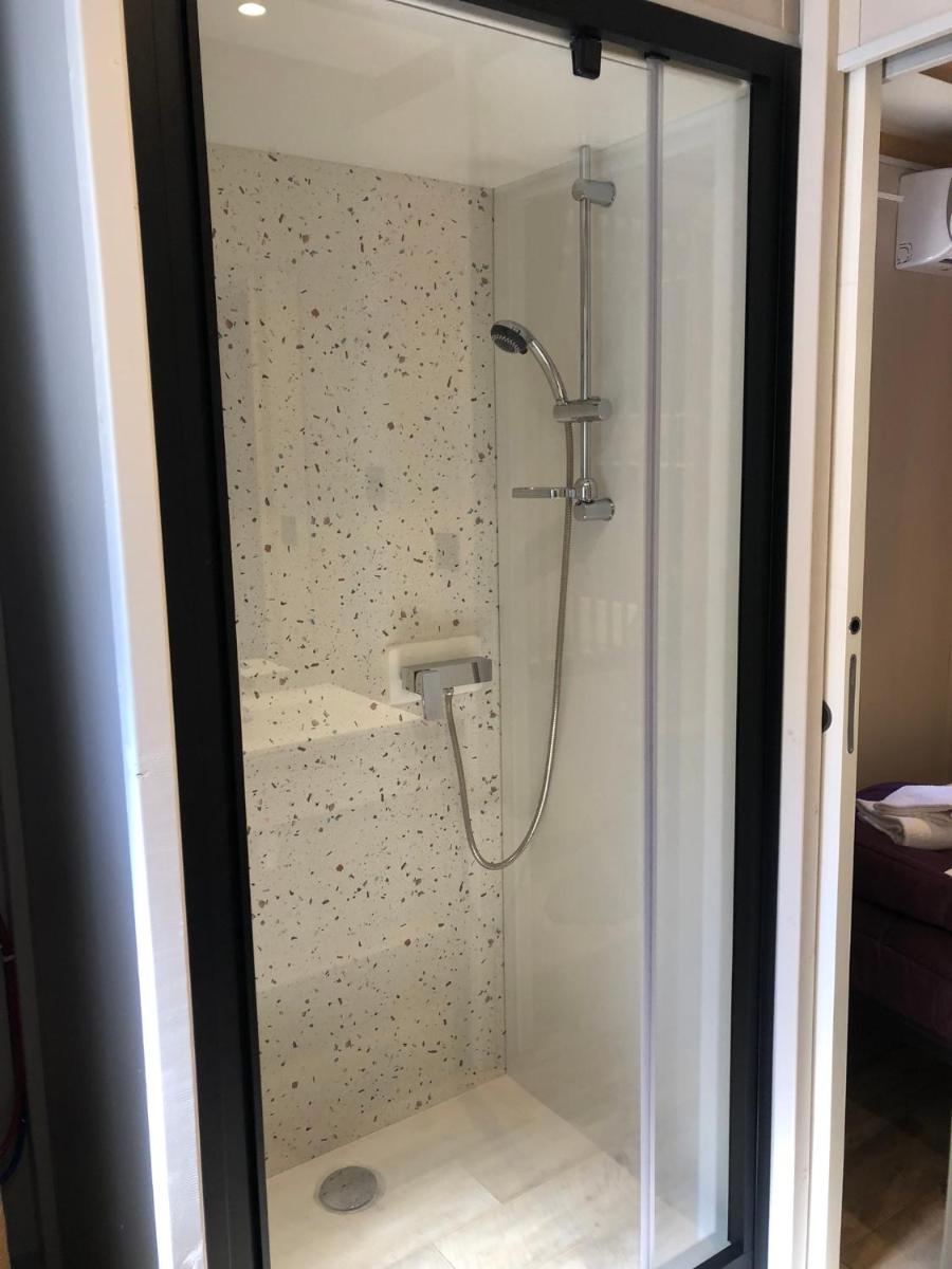une douche avec une porte vitrée dans une salle de bain dans l'établissement Camping La Pinède, à Calvi