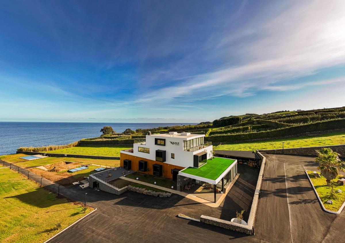 uma casa branca com telhado verde perto do oceano em Xhale Azores em Angra do Heroísmo