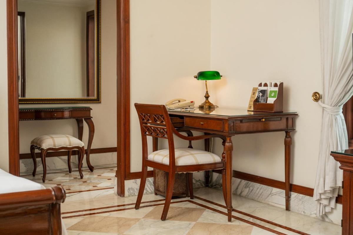 a bedroom with a desk with a lamp and a telephone at The Imperial, New Delhi in New Delhi a bedroom with a desk with a lamp and a telephone at The Imperial, New Delhi in New Delhi
