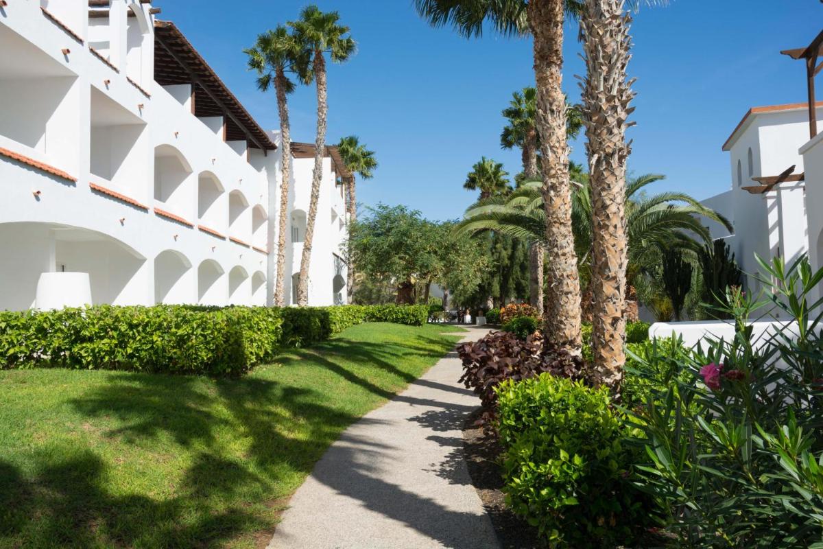 una pasarela frente a un edificio con palmeras en Club Jandía Princess, en Playa de Jandía