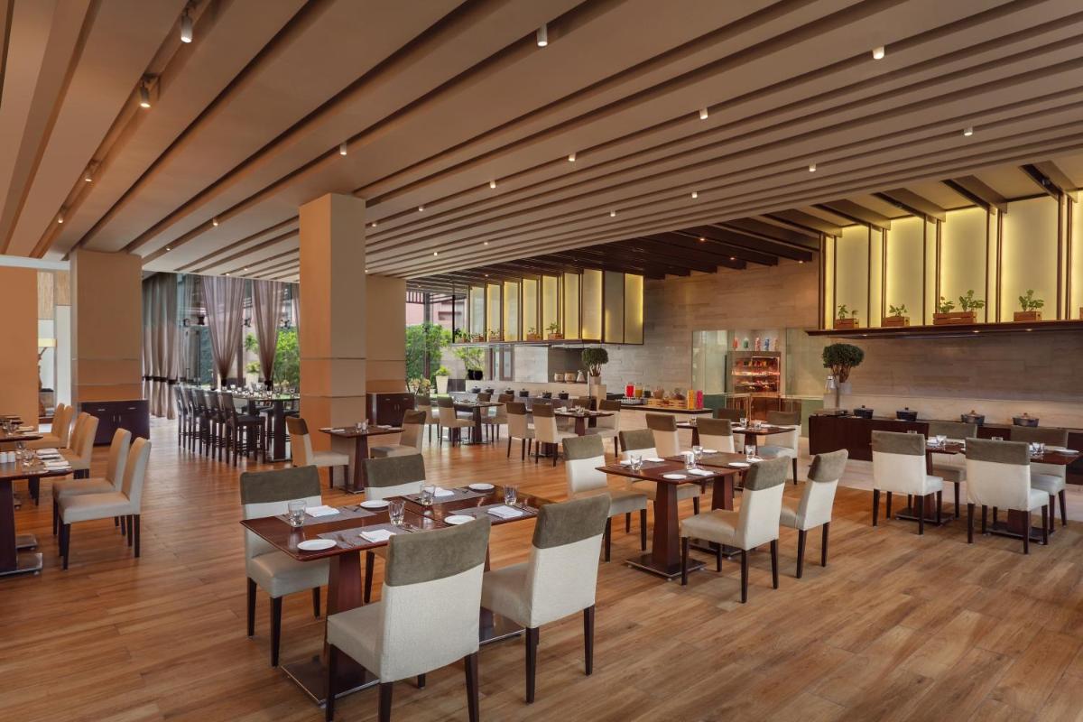 a dining room with tables and chairs in a restaurant at DoubleTree by Hilton Gurugram Baani Square in Gurgaon
