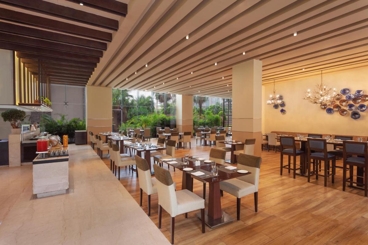 a restaurant with tables and chairs in a room at DoubleTree by Hilton Gurugram Baani Square in Gurgaon