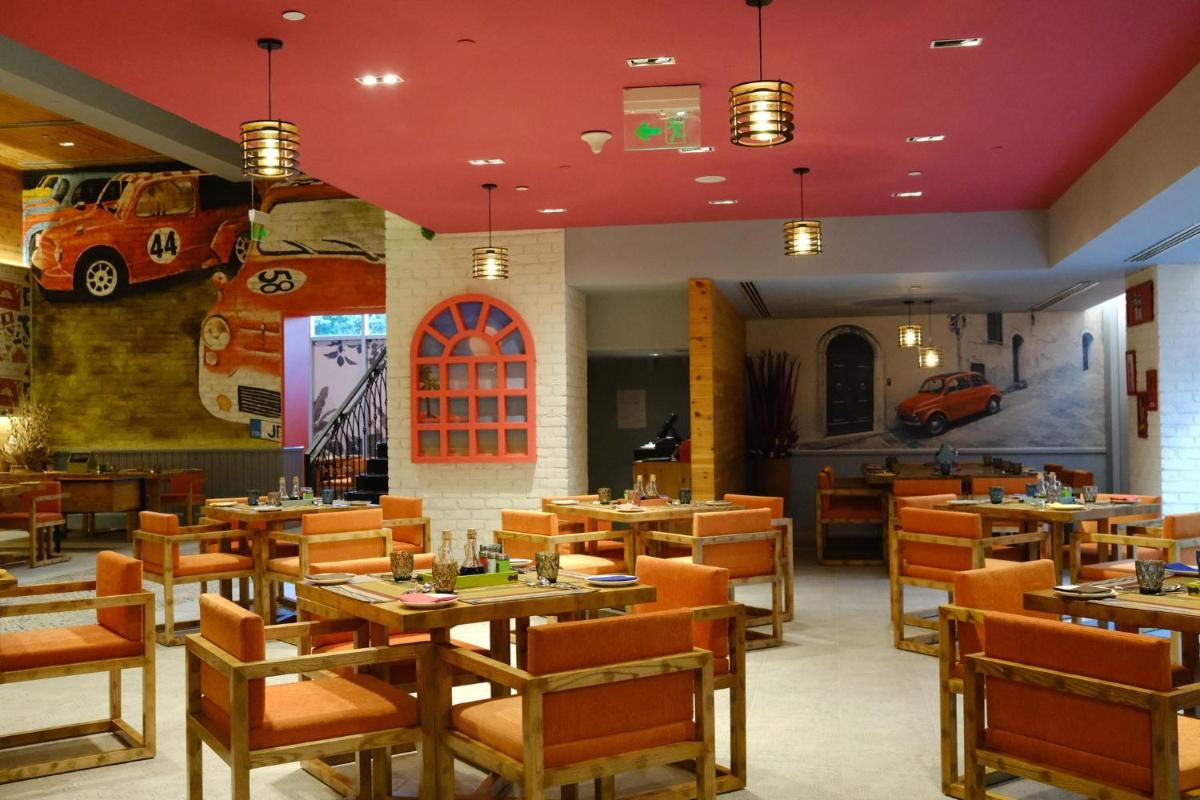 a restaurant with wooden tables and chairs and a car mural at Holiday Inn New Delhi Aerocity by IHG in New Delhi
