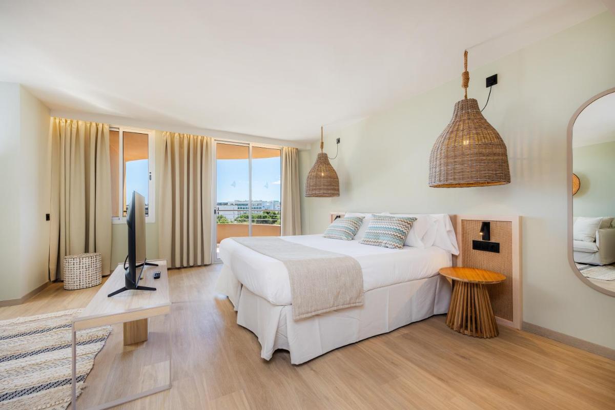 Un dormitorio blanco con una cama grande y un televisor. en Marins Beach Club - Adults Only Hotel, en Cala Millor