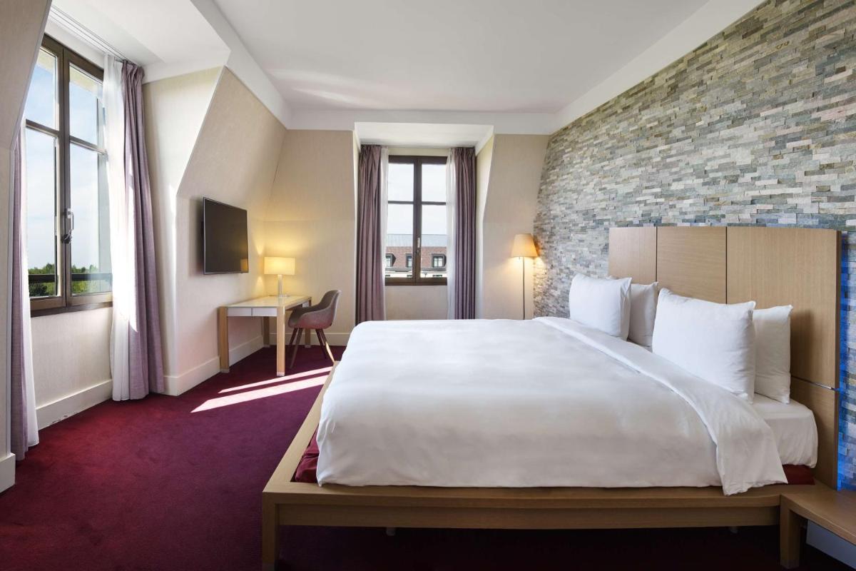 une chambre d'hôtel avec un grand lit et un bureau dans l'établissement Hotel Paris Marne-la-Vallee by IHG, à Magny-le-Hongre