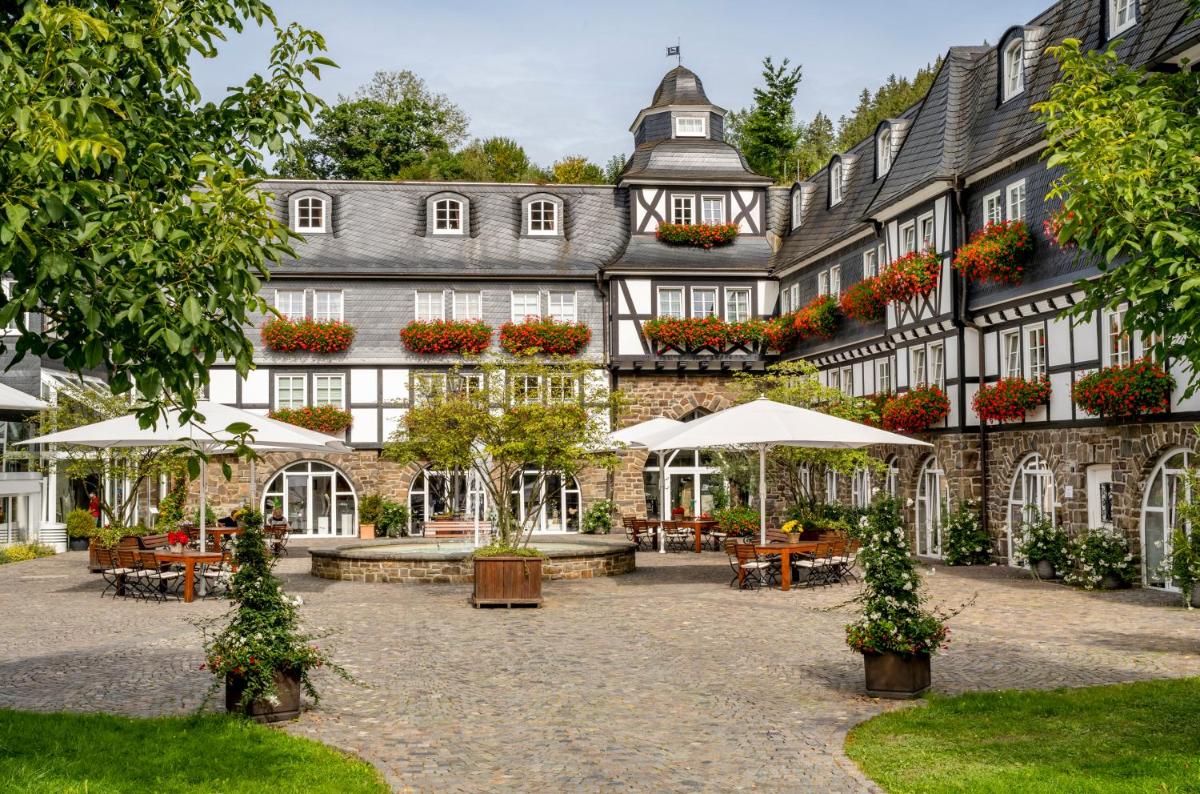 ein Gebäude mit Tischen und Sonnenschirmen in einem Innenhof in der Unterkunft Hotel Deimann in Schmallenberg