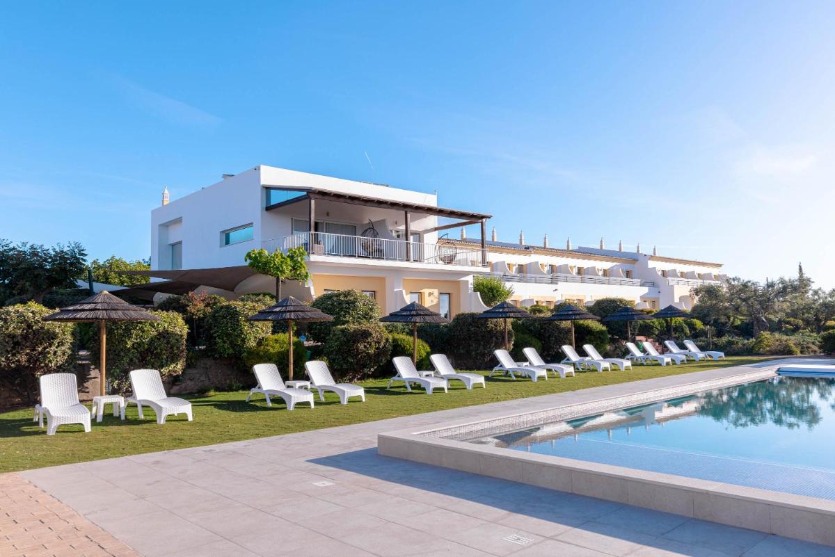 um resort com piscina, cadeiras e um prédio em Hotel Rural Quinta do Marco - Nature & Dining em Tavira