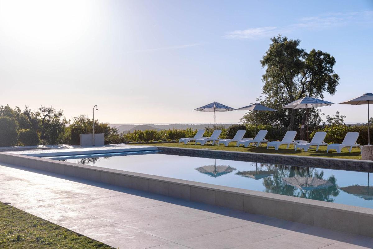 uma piscina com cadeiras e guarda-sóis em Hotel Rural Quinta do Marco - Nature & Dining em Tavira