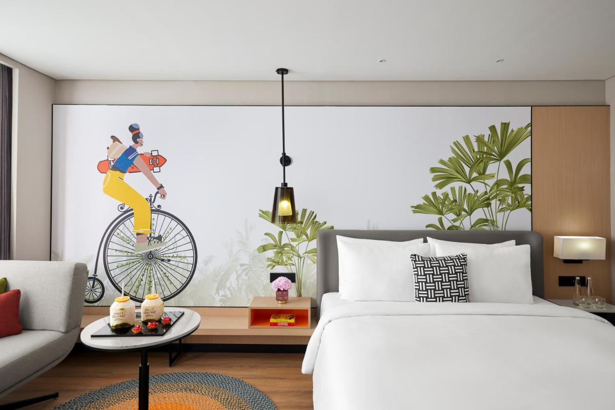 a bedroom with a bed and a woman riding a bike at Hyatt Centric Hebbal Bengaluru in Bengaluru