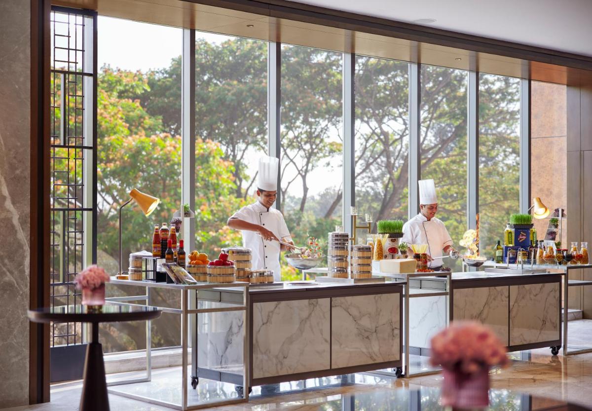 three chefs preparing food in a kitchen with windows at Hyatt Centric Hebbal Bengaluru in Bengaluru