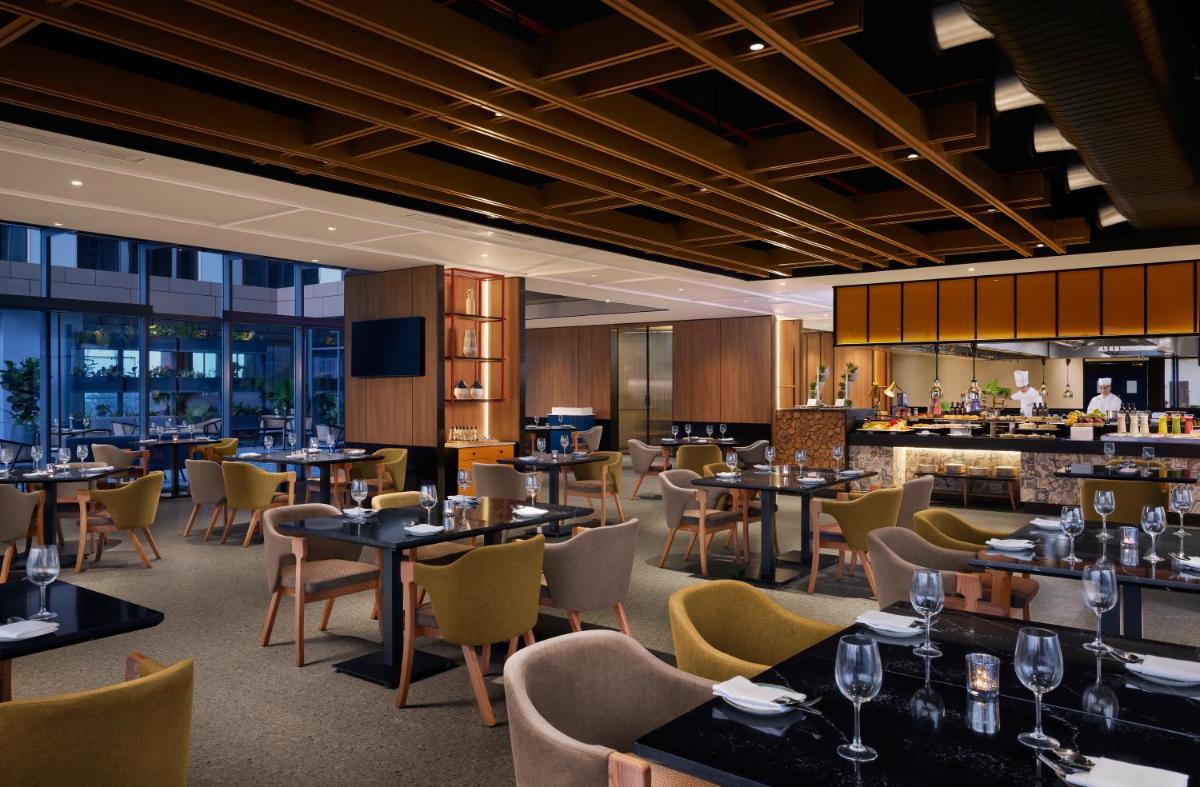 a restaurant with tables and chairs and a bar at Hyatt Centric Hebbal Bengaluru in Bengaluru
