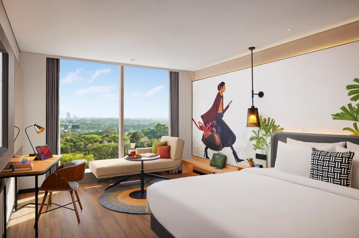 a hotel room with a bed and a large window at Hyatt Centric Hebbal Bengaluru in Bengaluru
