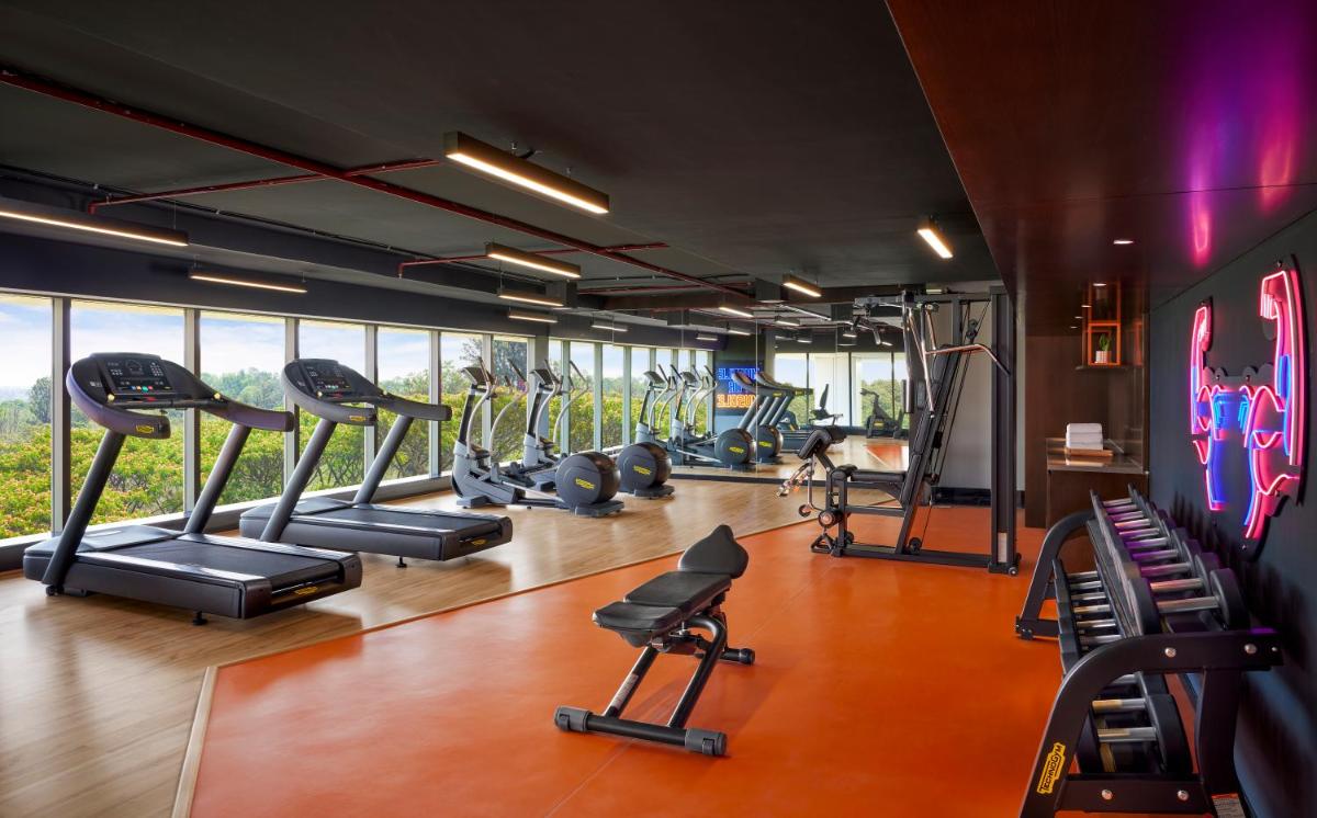a gym with treadmills and machines in a room at Hyatt Centric Hebbal Bengaluru in Bengaluru