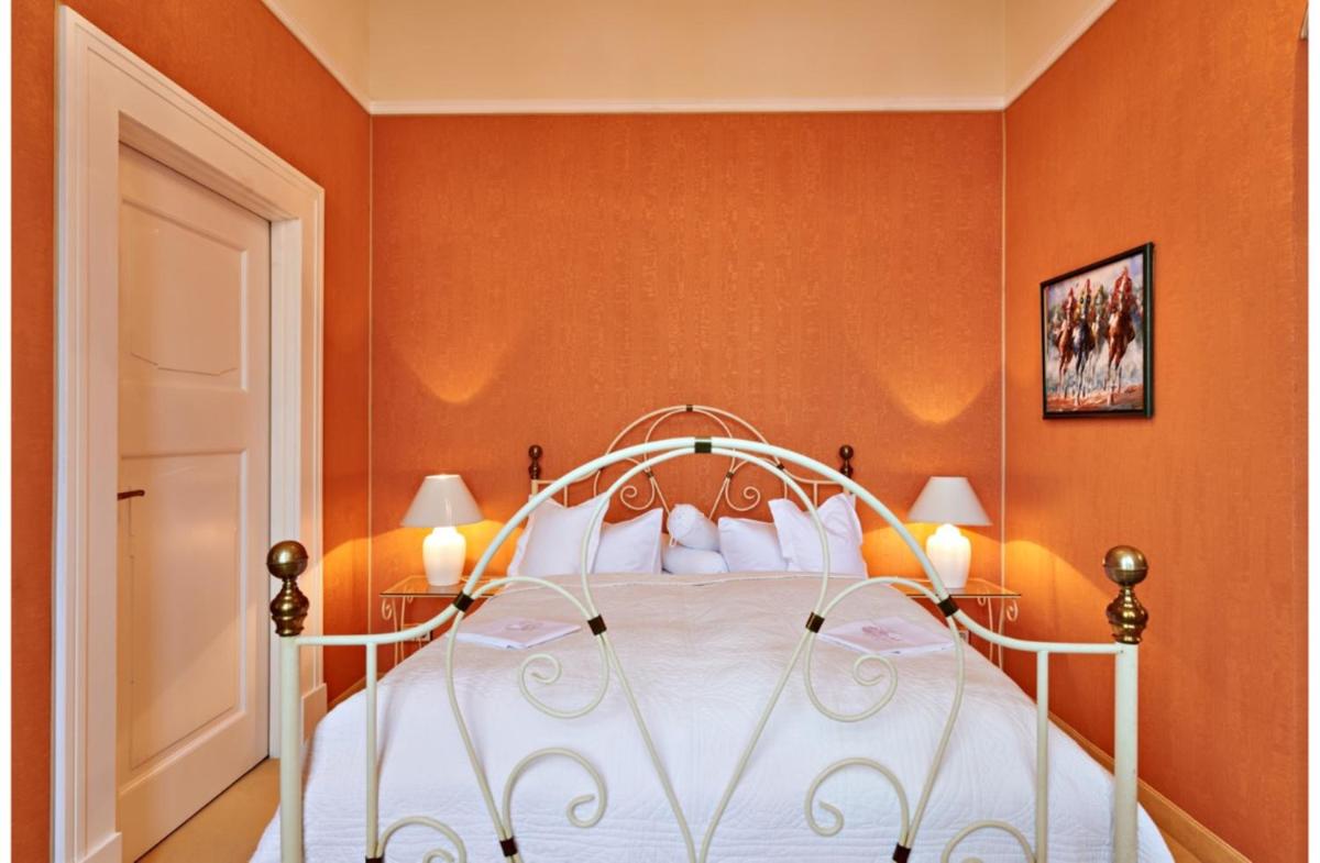 ein Schlafzimmer mit einem weißen Bett mit orangefarbenen Wänden in der Unterkunft Bernsteinschloss in Wendorf