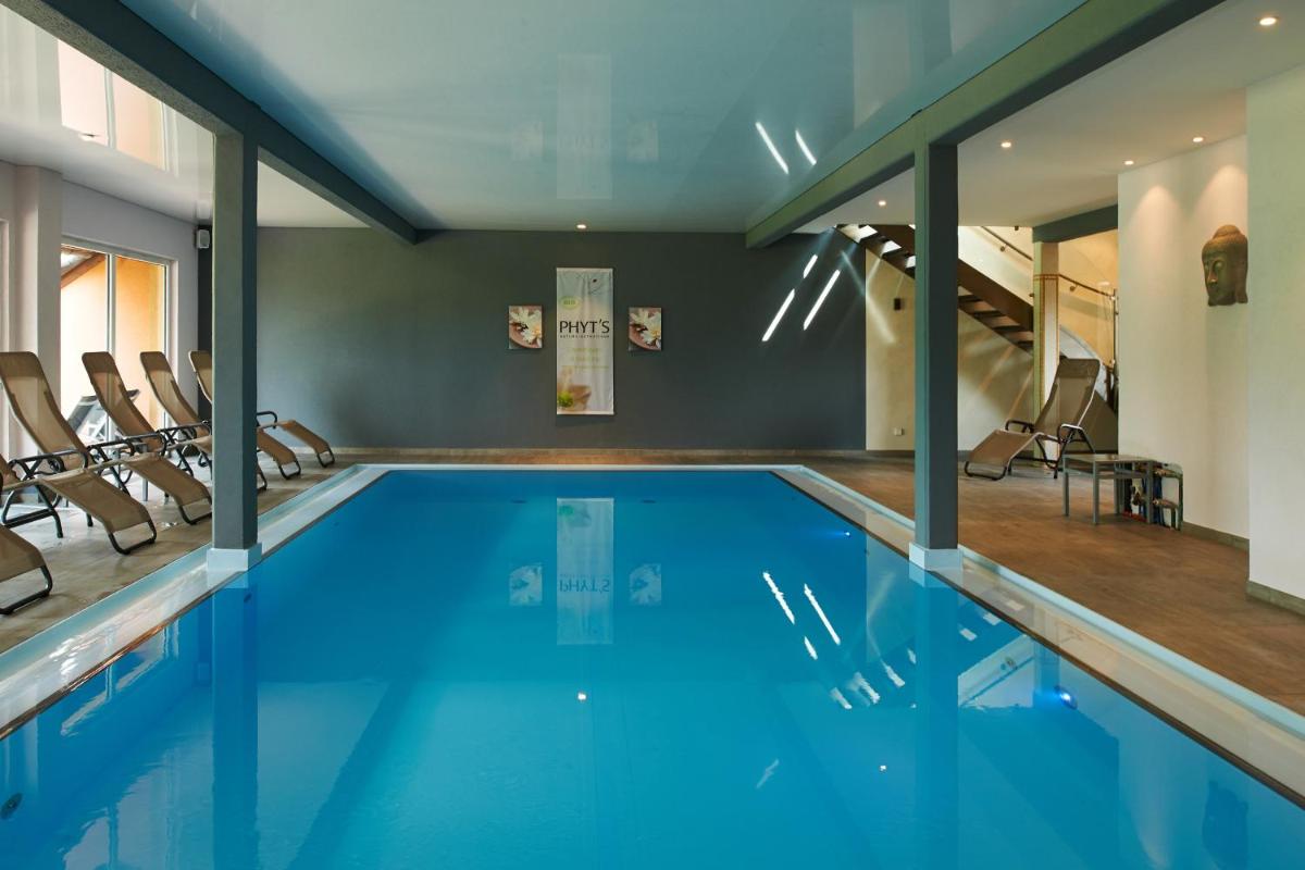 une piscine intérieure avec de l'eau bleue et des chaises dans l'établissement Hotel Spa et Restaurant Au Chasseur, à Birkenwald