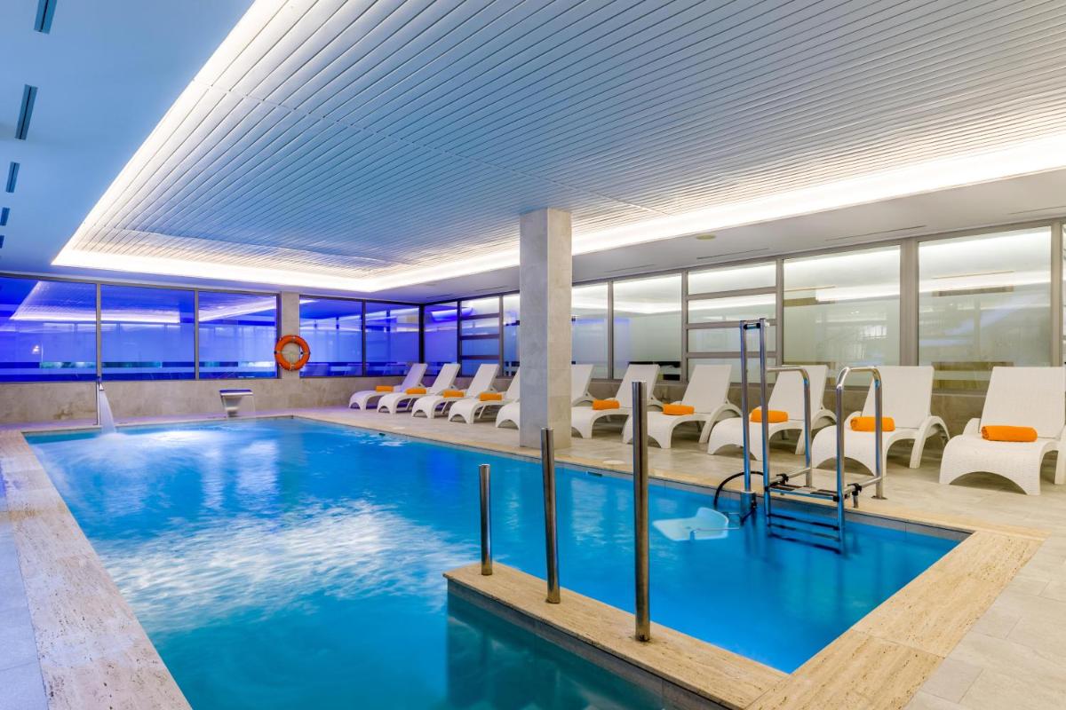 una gran piscina en un edificio con sillas blancas en VIVA Cala Mesquida Resort & Spa, en Cala Mesquida
