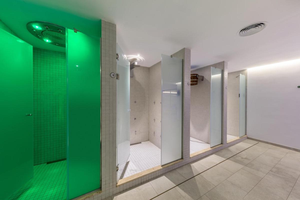 baño con cabina de ducha de cristal verde en VIVA Cala Mesquida Resort & Spa, en Cala Mesquida