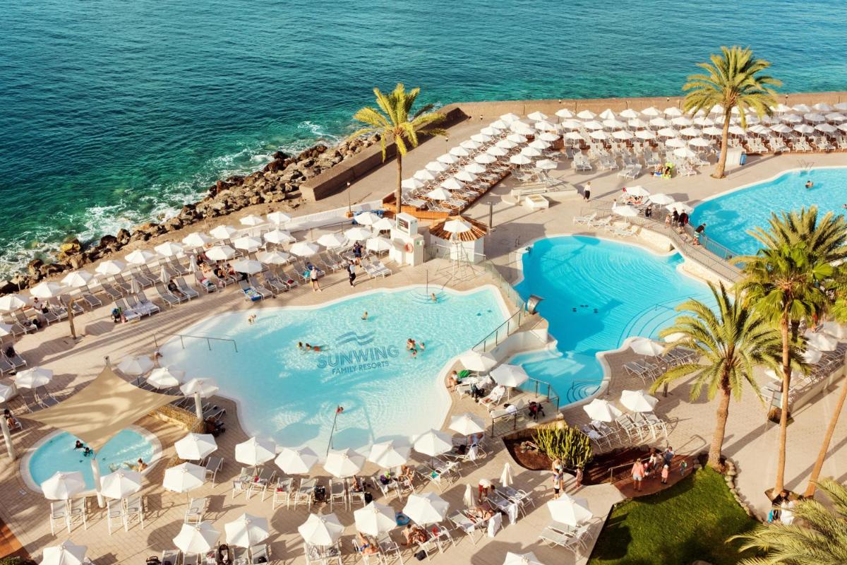 Una vista aérea de dos piscinas y el océano. en Sunwing Arguineguin Seafront, en Las Palmas de Gran Canaria