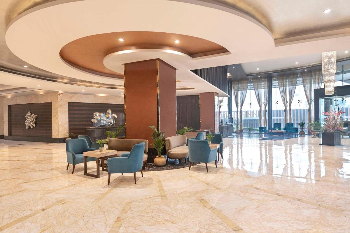 a lobby with chairs and tables in a building at Radisson Blu Kaushambi Delhi NCR in Ghaziabad
