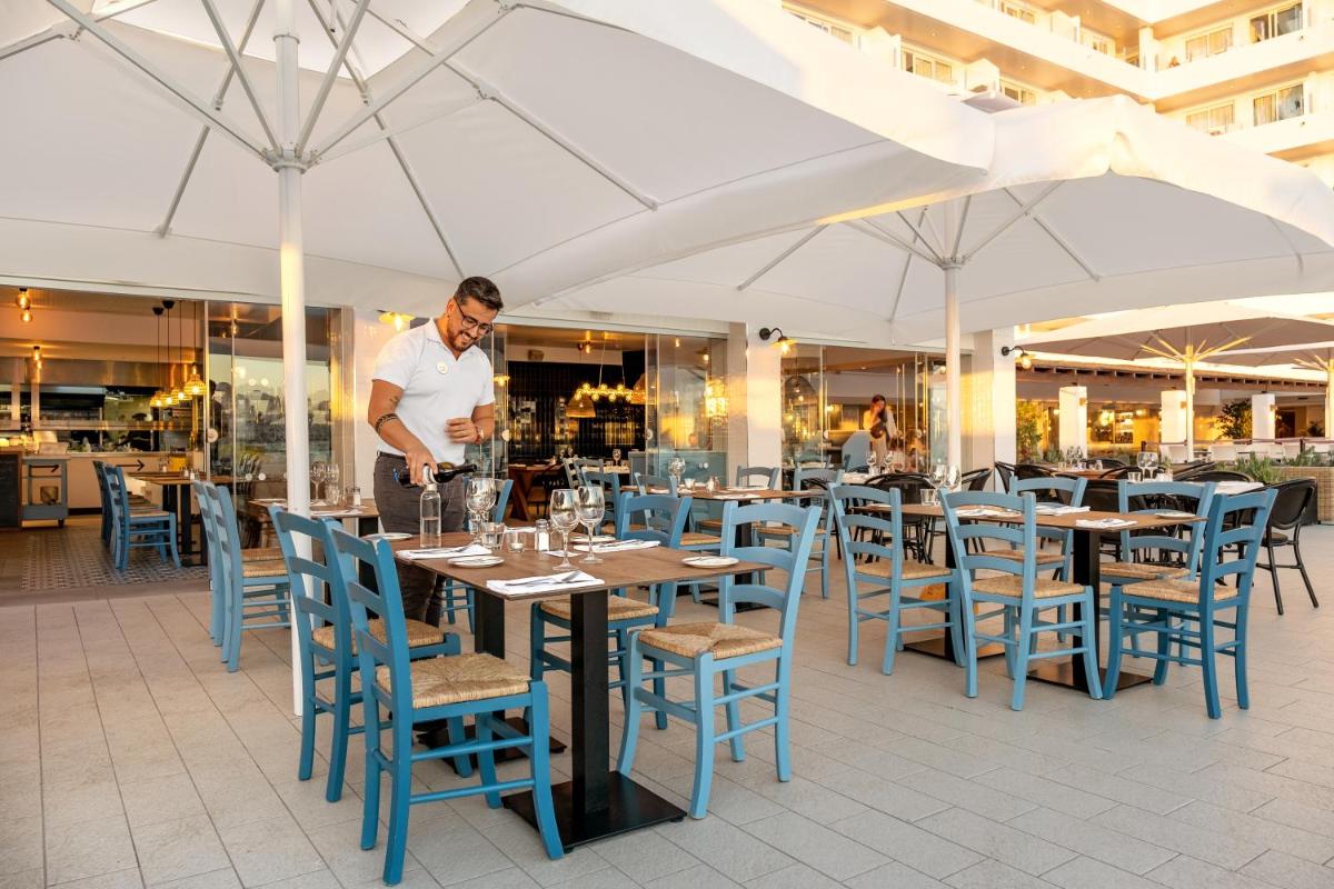 un hombre parado en una mesa en un restaurante en Sunwing Arguineguin Seafront, en Las Palmas de Gran Canaria