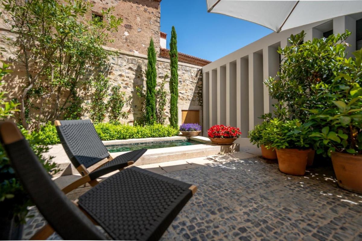 un patio con sillas, plantas y sombrilla en Atrio, en Cáceres