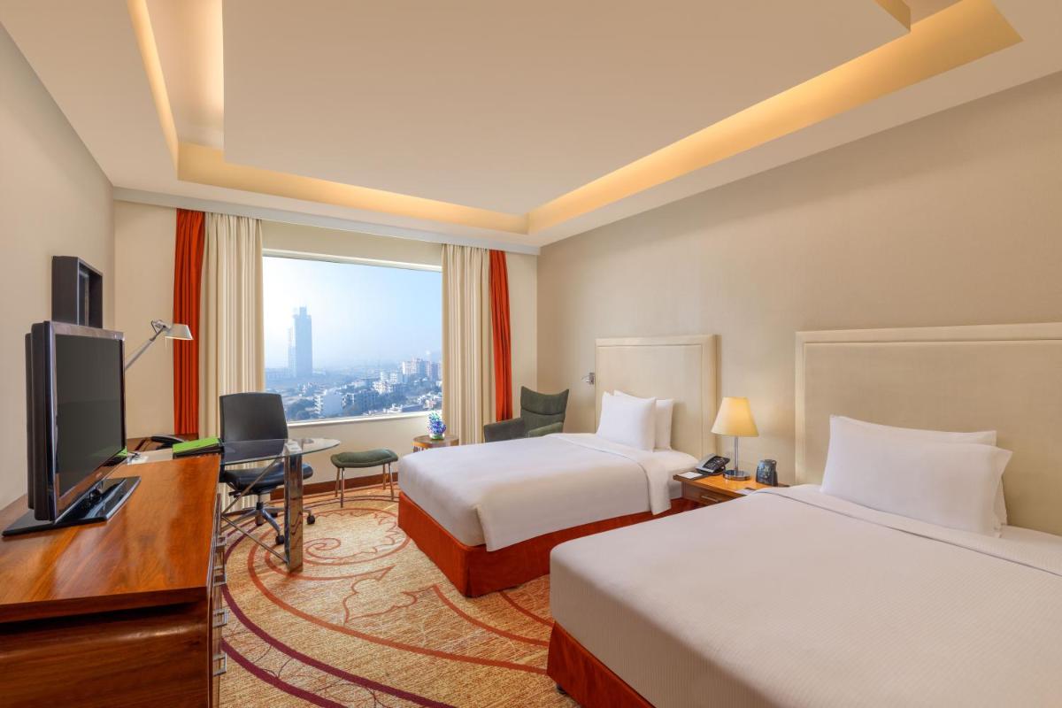a hotel room with two beds and a desk and a television at DoubleTree by Hilton Gurgaon New Delhi NCR in Gurgaon