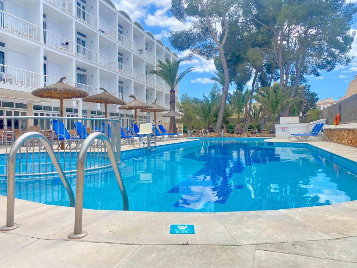 una piscina en un hotel con sillas y sombrillas en Hotel Isla de Cabrera, en Colonia de Sant Jordi