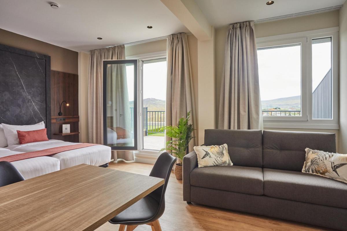 Una habitación de hotel con una cama, un sofá y una mesa. en Apartamentos Silken Fontibre Iberia & Spa, en Nestares 52 fotos más