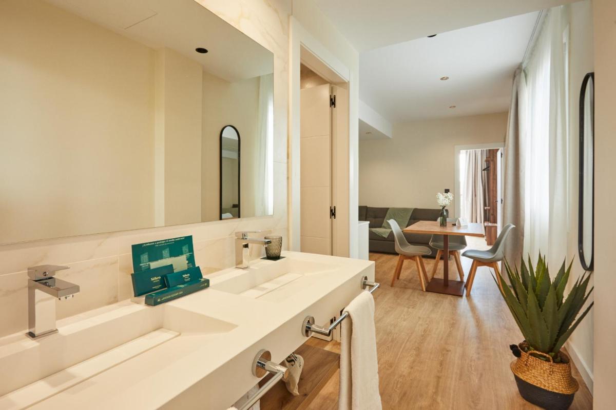 Un baño blanco con dos lavabos y una mesa. en Apartamentos Silken Fontibre Iberia & Spa, en Nestares
