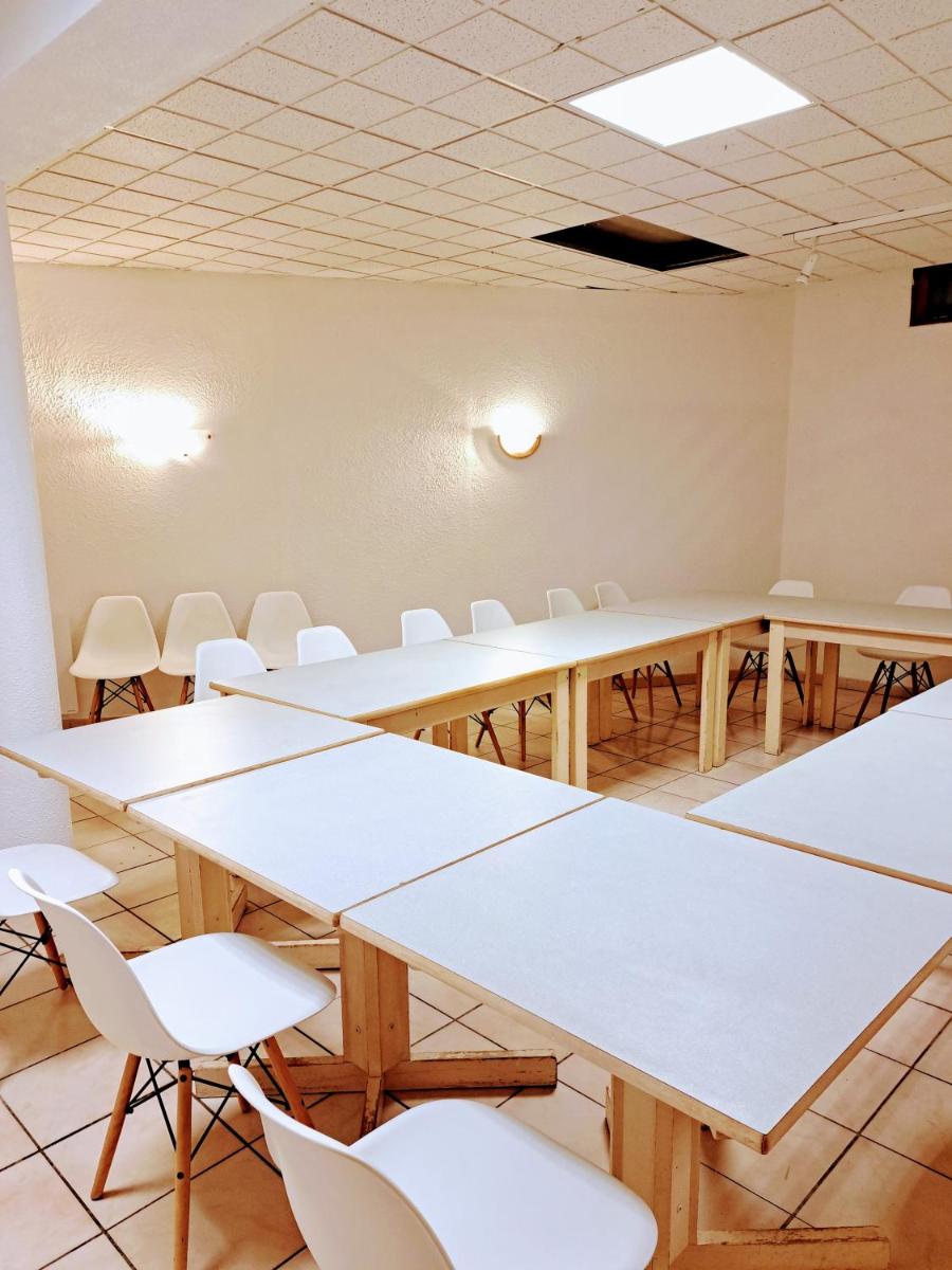 une salle de conférence avec des tables et des chaises blanches dans l'établissement Hôtel Espace Montclar, à Montclar