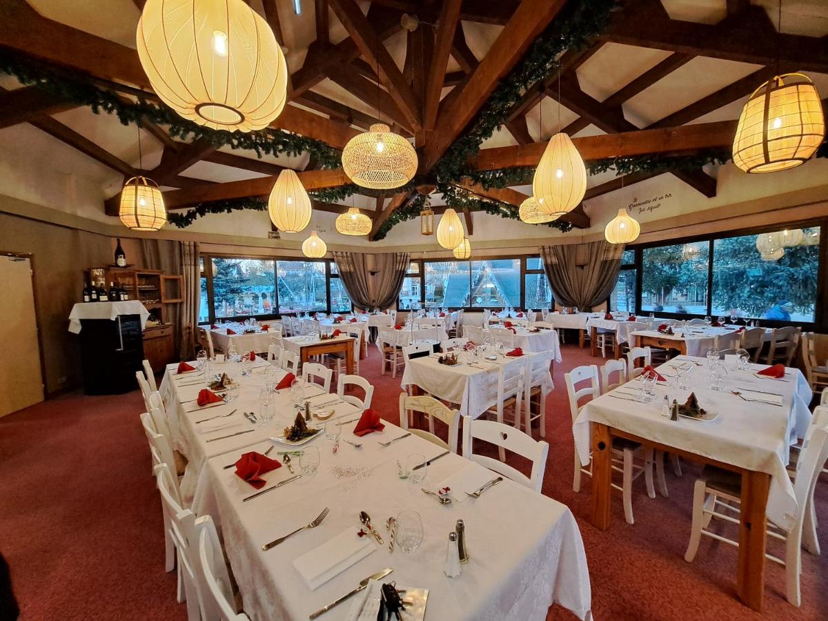 une salle à manger avec des tables et des chaises blanches et des lustres dans l'établissement Hôtel Espace Montclar, à Montclar