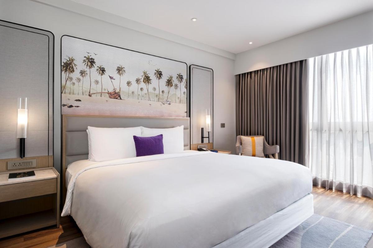 a bedroom with a large white bed with purple pillows at Vivanta Goa, Miramar in Panaji a bedroom with a large white bed with purple pillows at Vivanta Goa, Miramar in Panaji