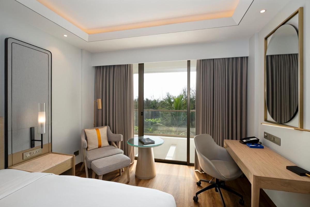 a hotel room with a bed and a desk and chair at Vivanta Goa, Miramar in Panaji a hotel room with a bed and a desk and chair at Vivanta Goa, Miramar in Panaji