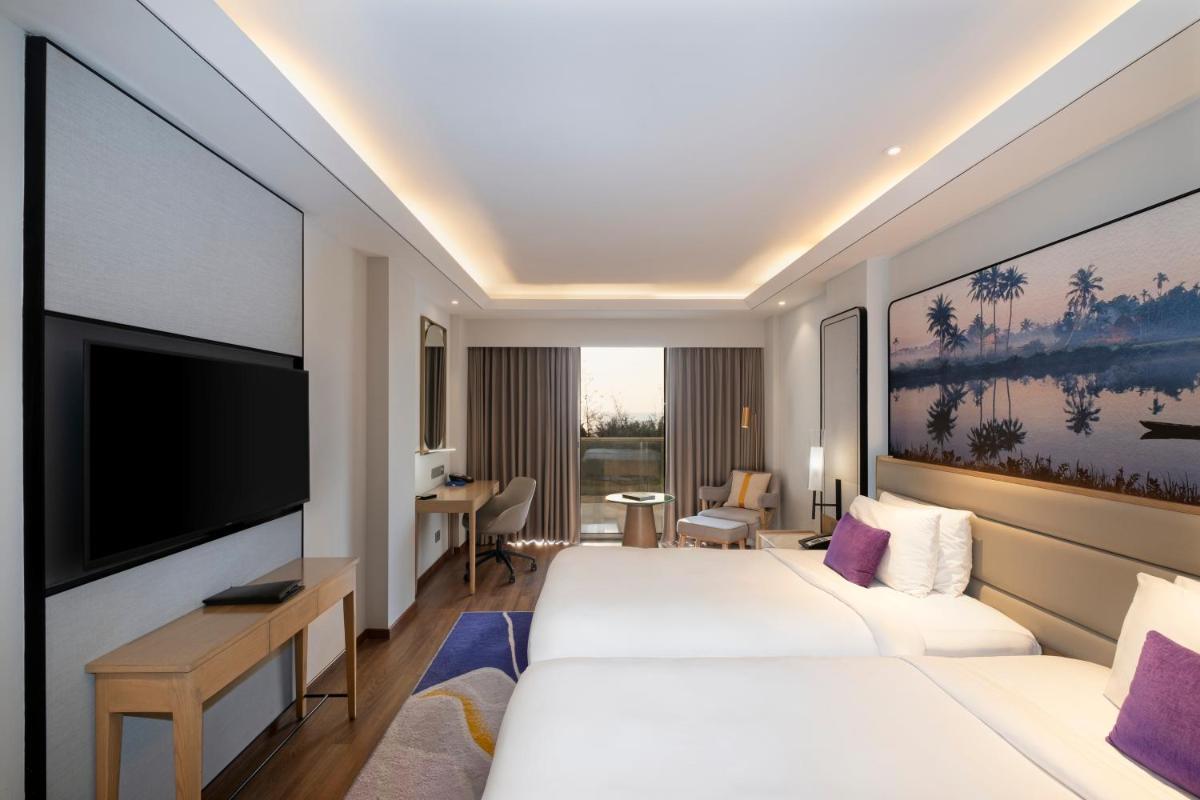 a hotel room with two beds and a flat screen tv at Vivanta Goa, Miramar in Panaji a hotel room with two beds and a flat screen tv at Vivanta Goa, Miramar in Panaji